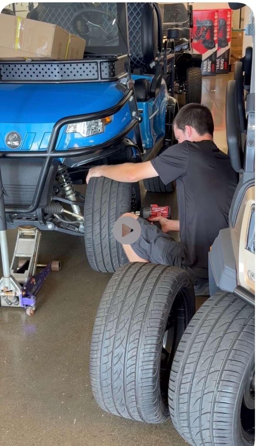 Technician working on a golf cart wheel and brake assembly.