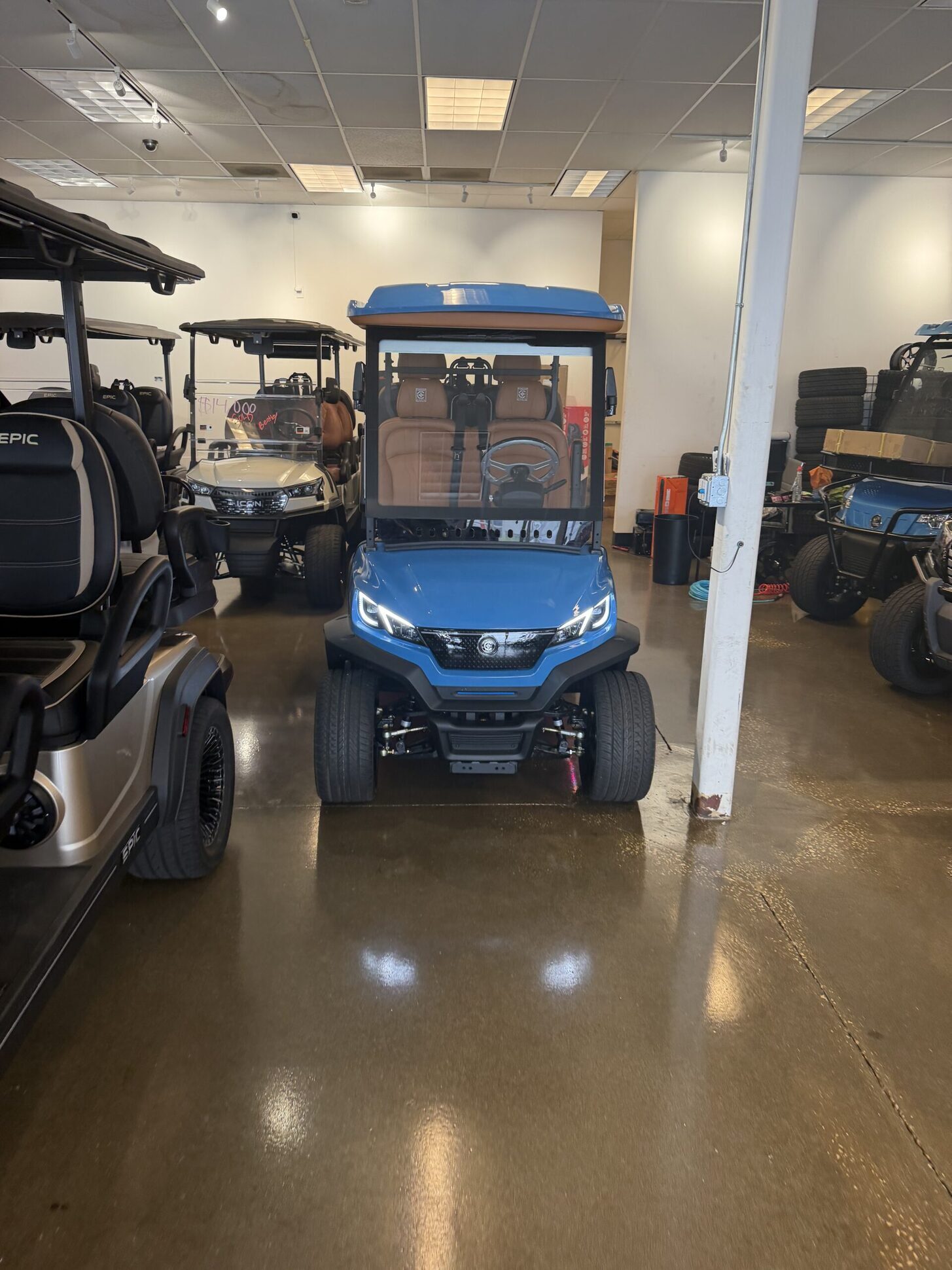 Electric-blue ICON four-passenger golf cart with cognac interior in the showroom.